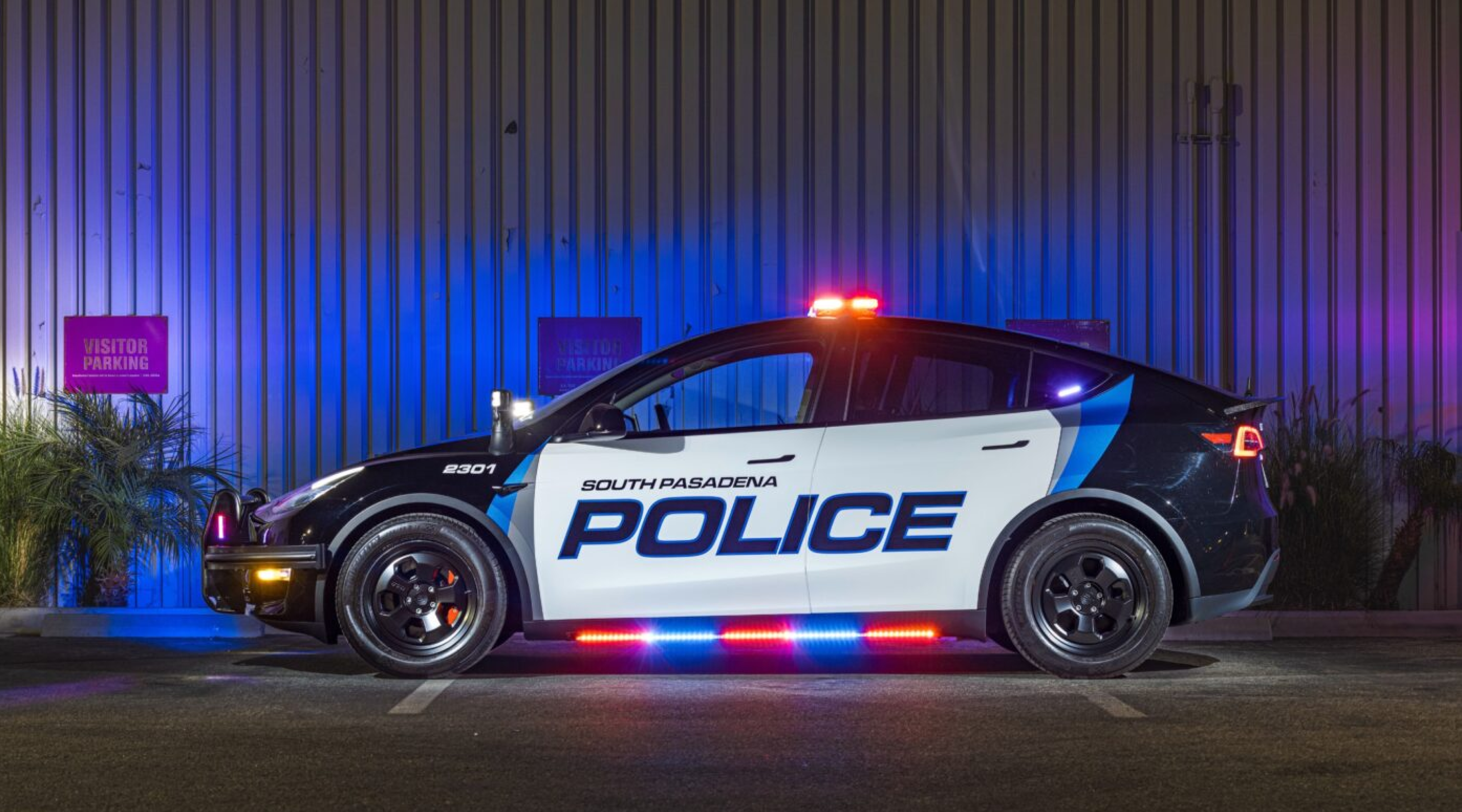 A police car with a black and white design, featuring blue lettering that reads 'SOUTH PASADENA POLICE'. The vehicle is parked in a lit area, displaying red and blue emergency lights.