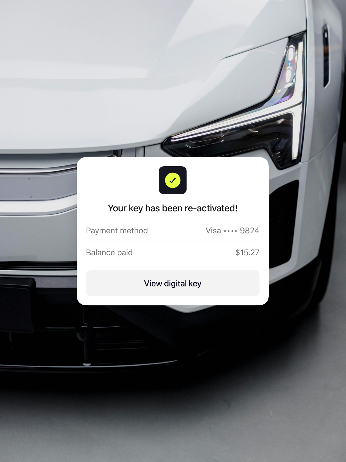 Close-up of a modern white car with a notification displayed on the screen. The message indicates key reactivation, showing payment method and balance paid.